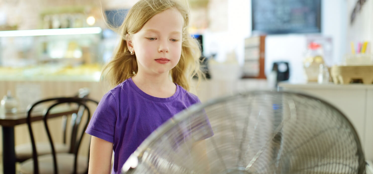 little girl in front of oscillating fan in kitchen dealing with common air conditioning problems