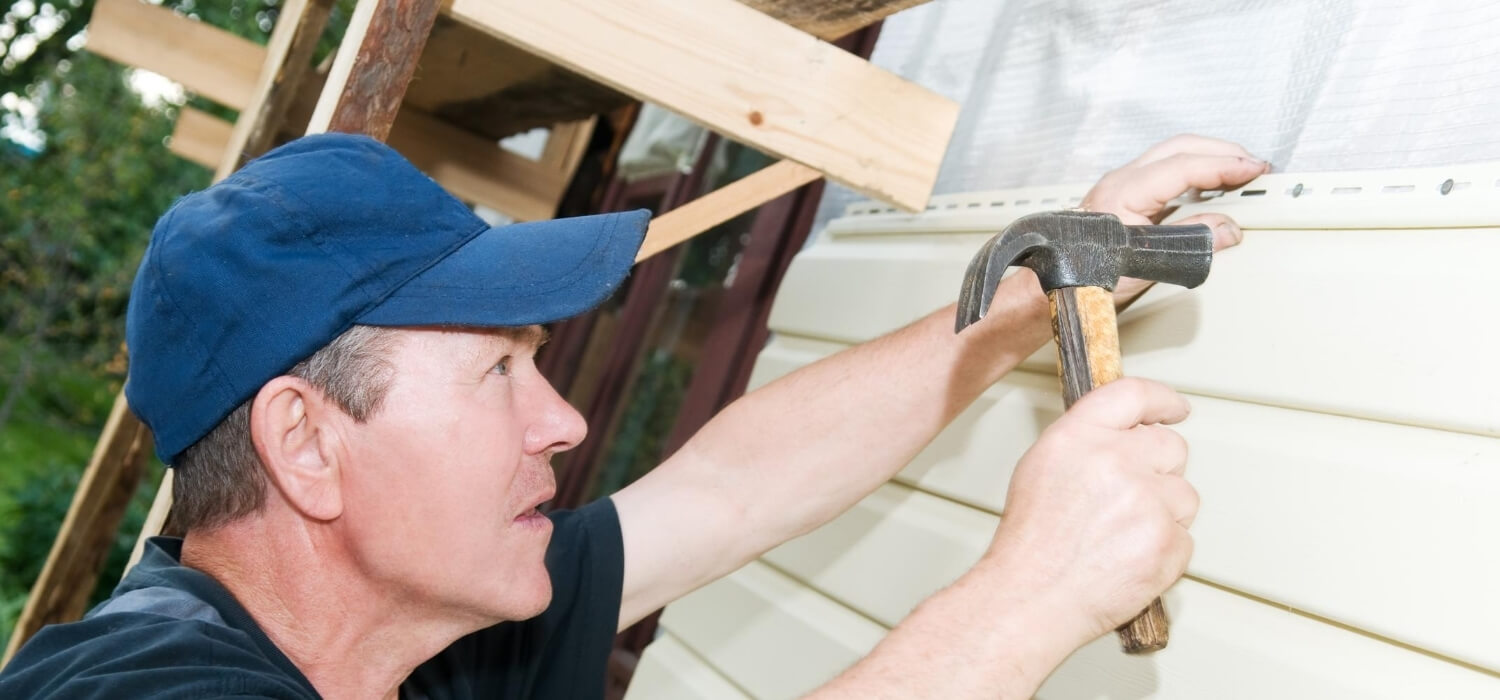 homeowner fixing siding on the house