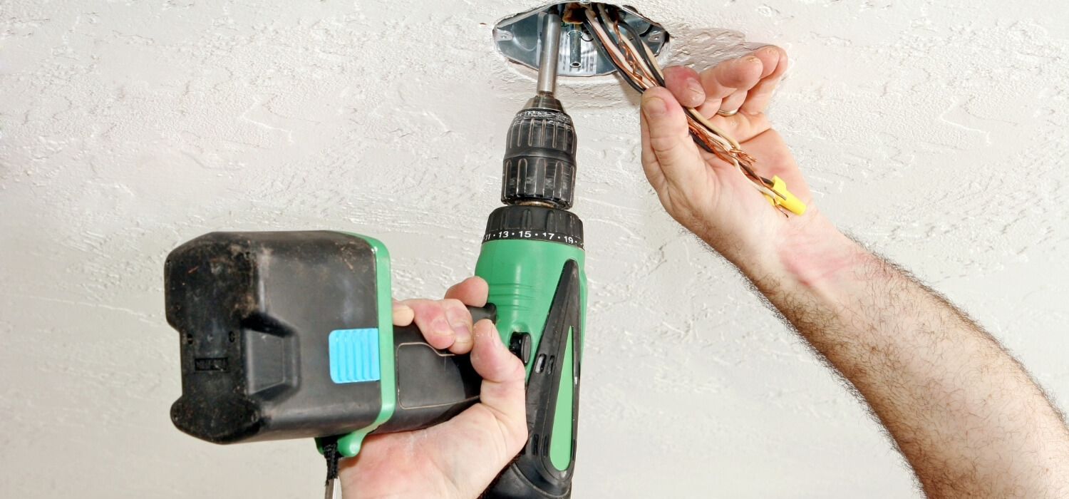 electrician fixing wires to light in ceiling