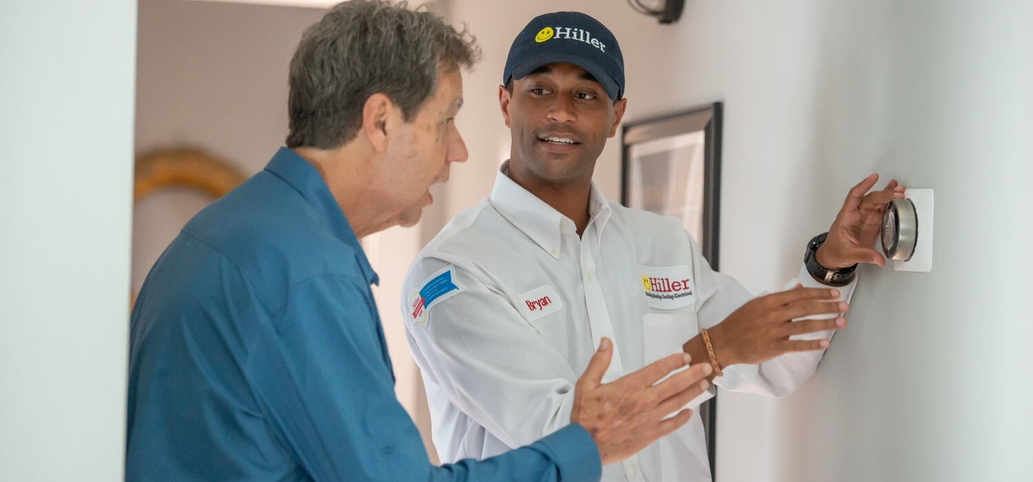 HVAC Technician Showing Customer Smart Thermostat