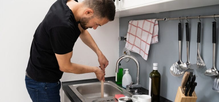 Homeowner Using Plunger on Kitchen Drain