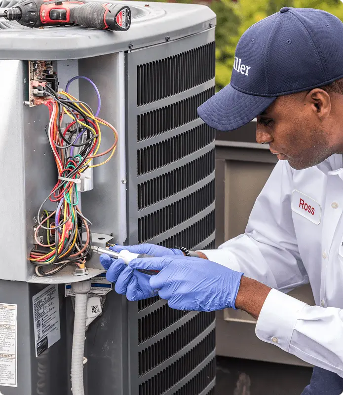 Hiller technician inspecting the defrost sensor array on a Lennox heat pump during a damp Nashville winter day.